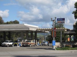 A wide angle photo of an ARCO station. ARCO and am/pm sign towers above the busy gas station.
