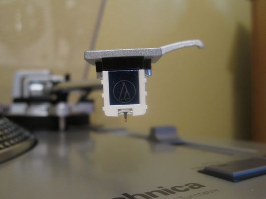 Close-up photo shows the cartridge and stylus on the Audio-Technica AT-LP120-USB.
