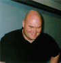 Photo shows Roger Binns' smiling and slightly bowing, showing his bald head.